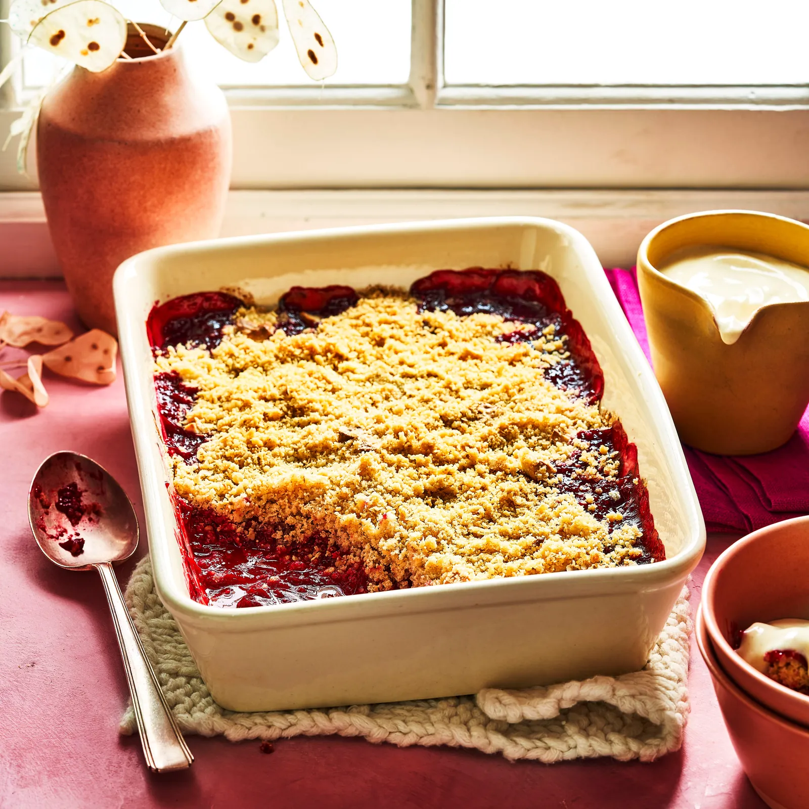 Pflaumen-Crumble mit dunkelroten Früchten unter goldenen Streuseln
